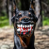 A black dog wearing a funny muzzle costume with fake blood dripping from its teeth.