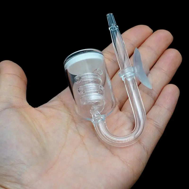 A clear aquarium CO2 diffuser with a suction cup is held in a person's hand.