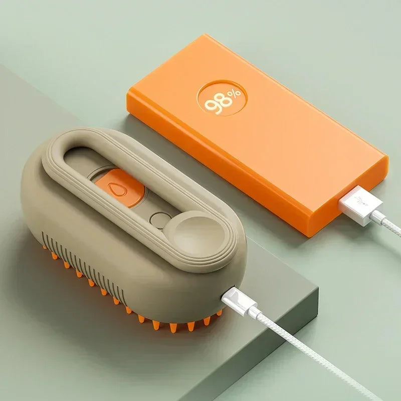Eine orange Box und eine beige Pflegbürste mit weißem Kabel auf einer grauen Oberfläche.