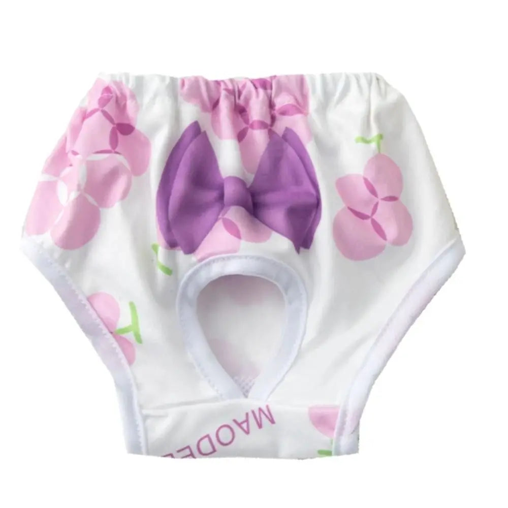 White reusable dog physiological pants with pink floral accents and a purple bow.