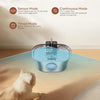A stainless steel cat water fountain is placed on a wooden floor with a white cat looking at it.