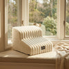 A beige pet safety climbing stairs product resting on a windowsill with blurred greenery outside.