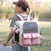 A woman is wearing a pink and white ventilated cat carrier backpack while standing outdoors.