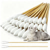 A bundle of long cotton swabs used for pet ear cleaning, with a gray cat resting nearby.