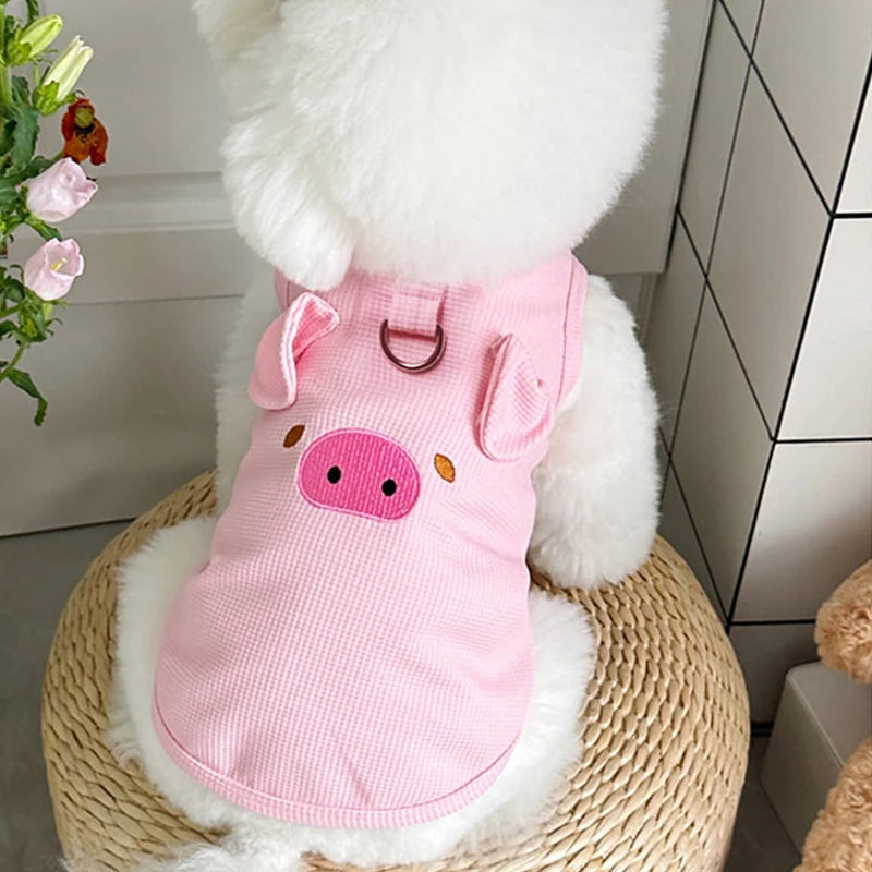 A pink waffle knit pet vest for a dog or cat is shown resting on a woven surface.