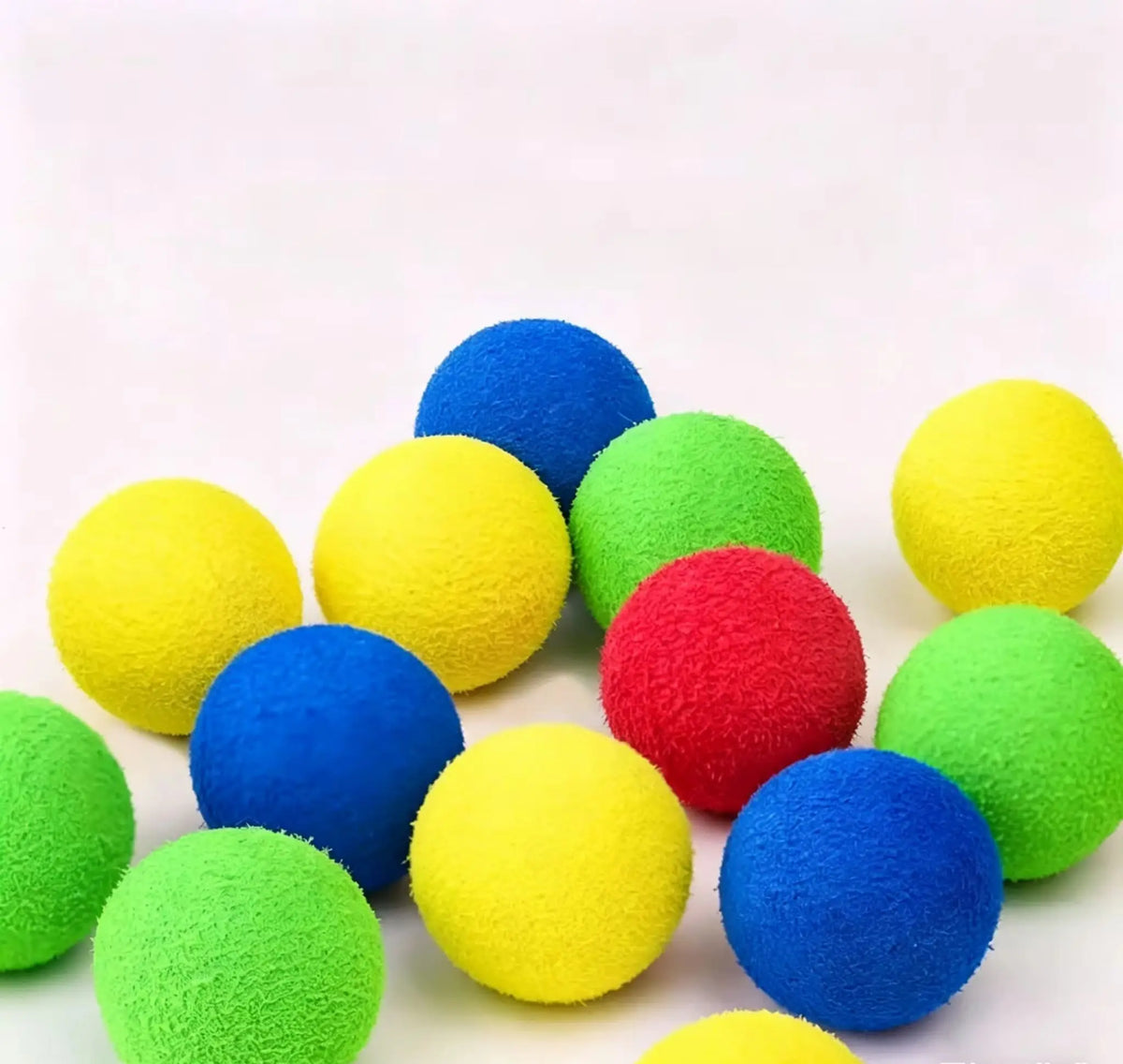 Eine Sammlung leuchtend bunter, flauschiger Spielbälle in Gelb, Blau, Grün und Rot.