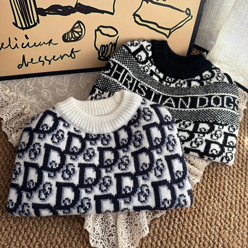 A black and white knit sweater featuring a repeating dog silhouette pattern is displayed on a wooden background.