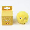 A yellow cardboard box with a cutout, next to a round, fluffy yellow cat toy.