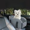 A small white dog is resting in a gray portable pet car bed with safety straps inside a car.