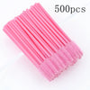 A bundle of 500 pink disposable eyelash and eyebrow brushes laid out on a white background.