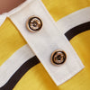 A close-up of a yellow polo shirt with white and black stripes featuring gold buttons.