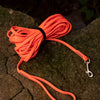 Orange heavy-duty waterproof dog leash coiled on a mossy rock.