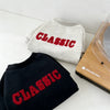 A gray classic letter print hoodie folded next to a wooden soundlook device.