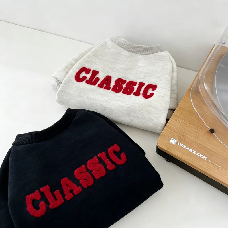 A gray classic letter print hoodie folded next to a wooden soundlook device.