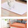 A fluffy white dog is sitting on a pink quilted mat in a modern living room setting.