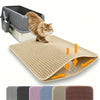 Ein flauschiger orange Kater steht auf einer beigen Katzenstreumatte neben einer grauen Katzentoilette.