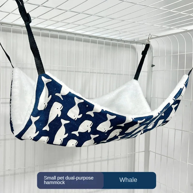 Eine kleine, zweckentfremdete Hammock, die wie eine Wal geformt ist, hängt in einem Drahtgitter.