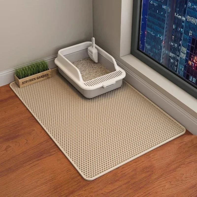 Un tapis de litière pour animaux waterproof blanc avec un plateau à grilles est placé sur un plancher en bois près d'une fenê