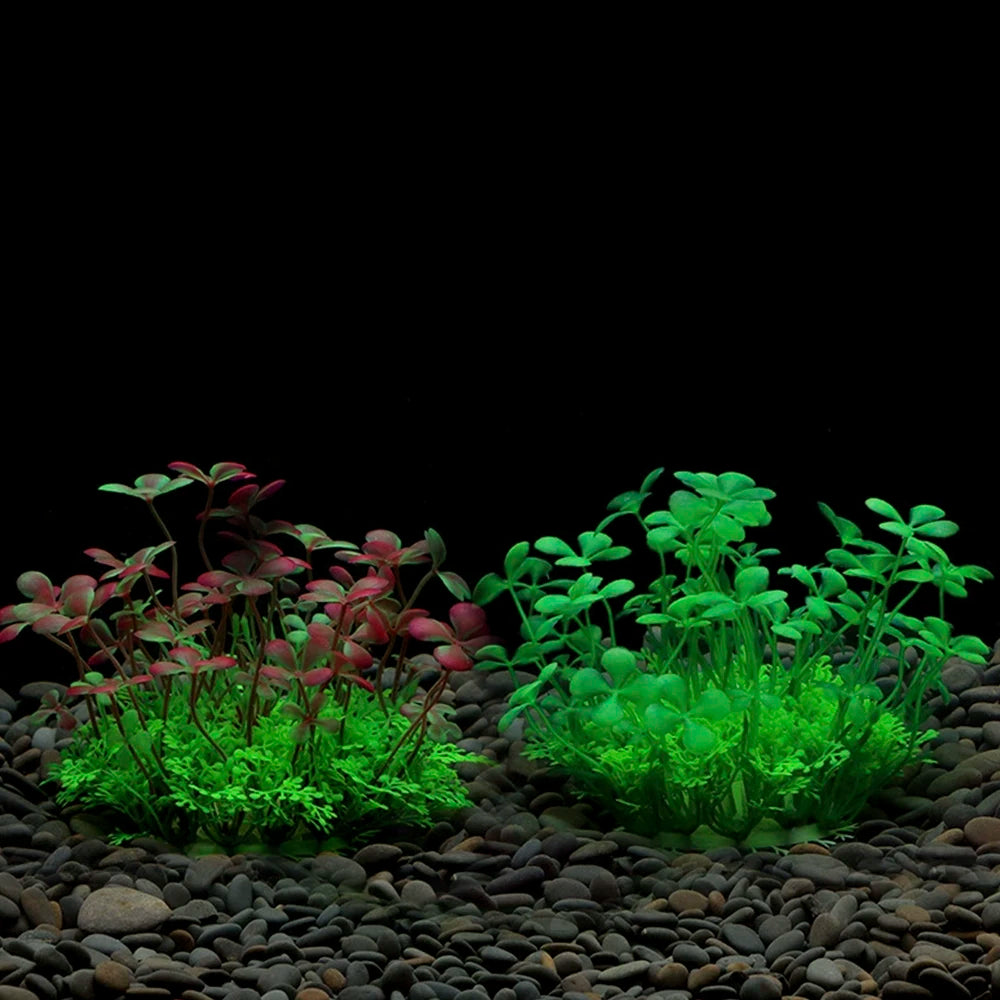 A display of vibrant artificial aquarium plants featuring red and bright green foliage on dark gravel.