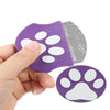A hand holds a purple mini pet grooming comb with white paw shapes on the head and a flat comb blade.