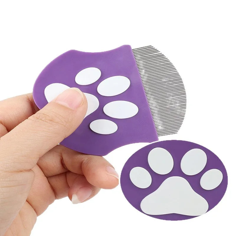 A hand holds a purple mini pet grooming comb with white paw shapes on the head and a flat comb blade.