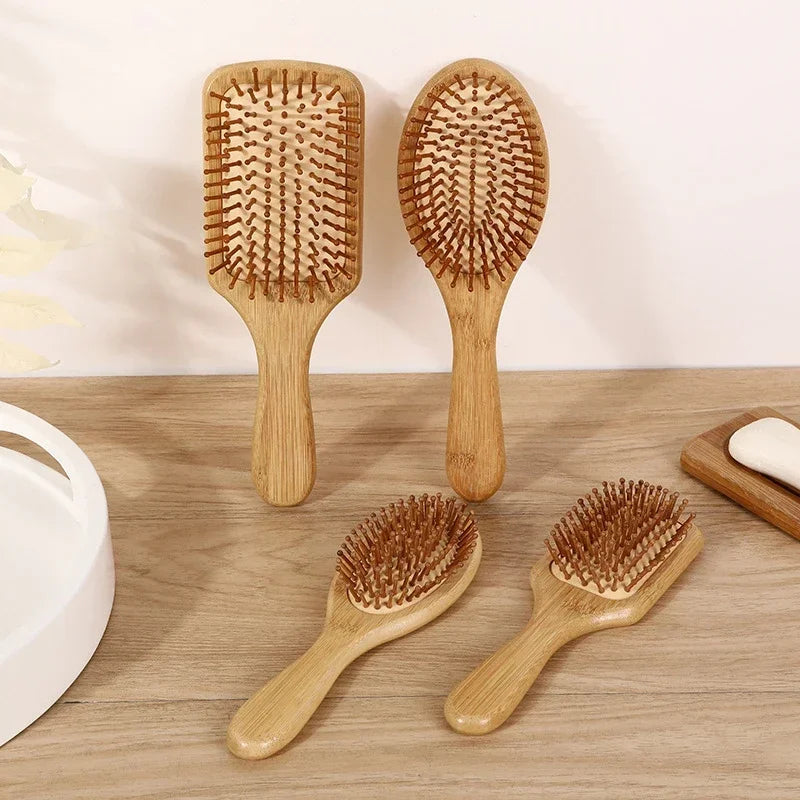 Three wooden bamboo hair brushes with massage bristles are displayed on a wooden surface.