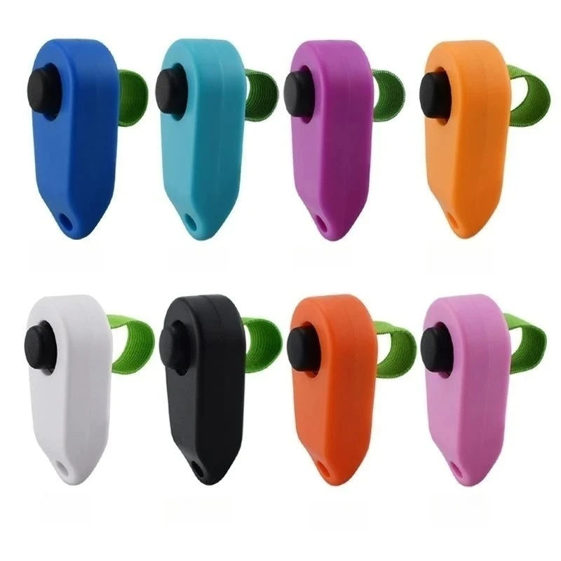 A set of colorful pet training clickers in various plastic colors including blue, teal, purple, orange, white, and black.