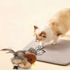 A fluffy orange and white cat toy shaped like a bird is resting on a gray mat.