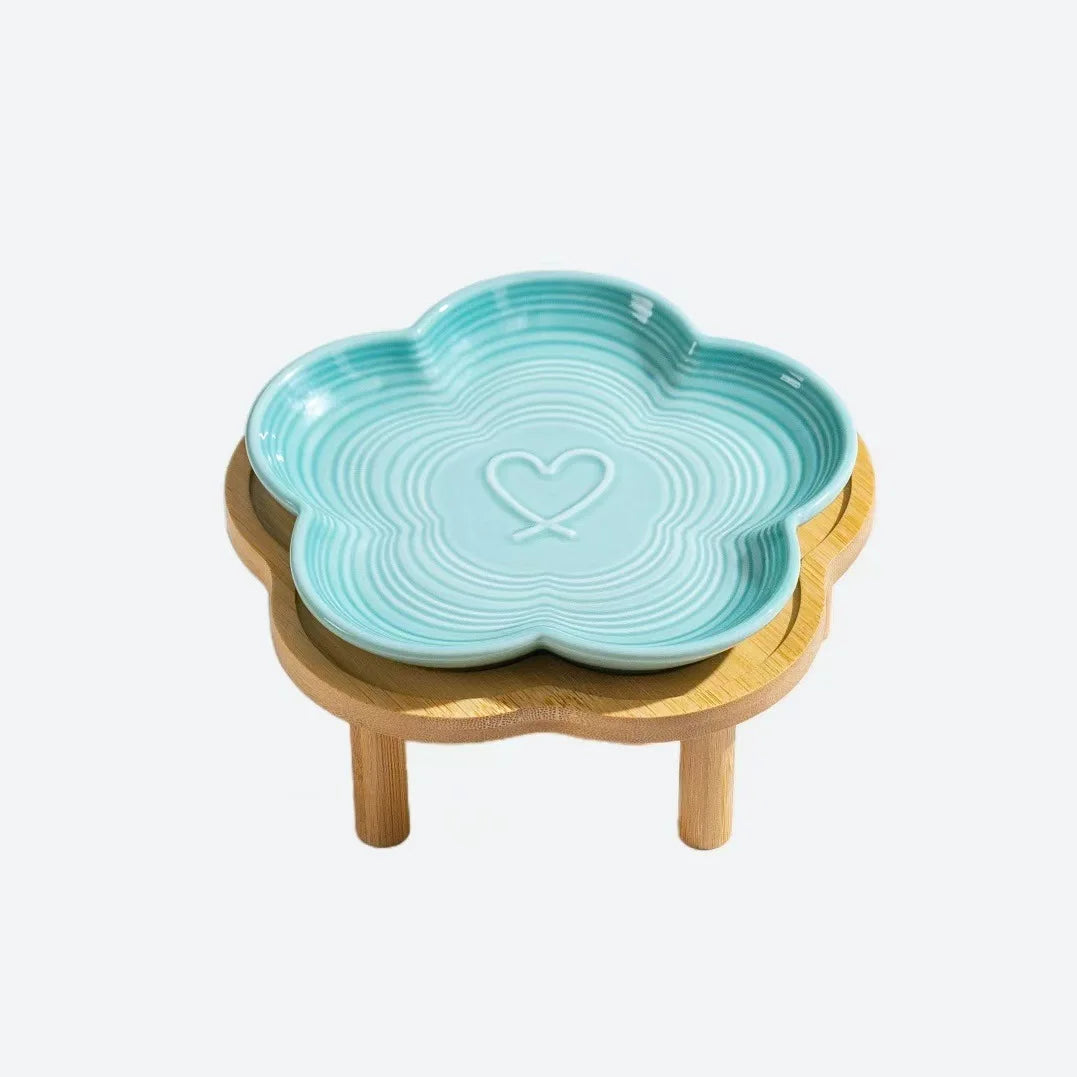 Bol à animaux en céramique bleu clair avec motif cœur, posé sur un support en bois naturel.