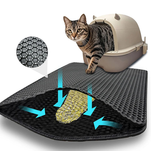 A tabby cat stands next to a black litter mat, demonstrating the mat's texture and function.