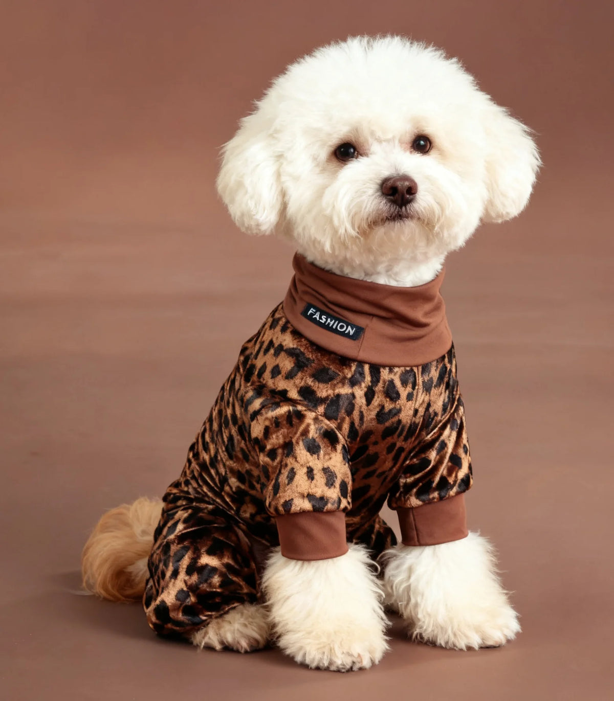 A fluffy white dog wearing brown leopard print pajamas.