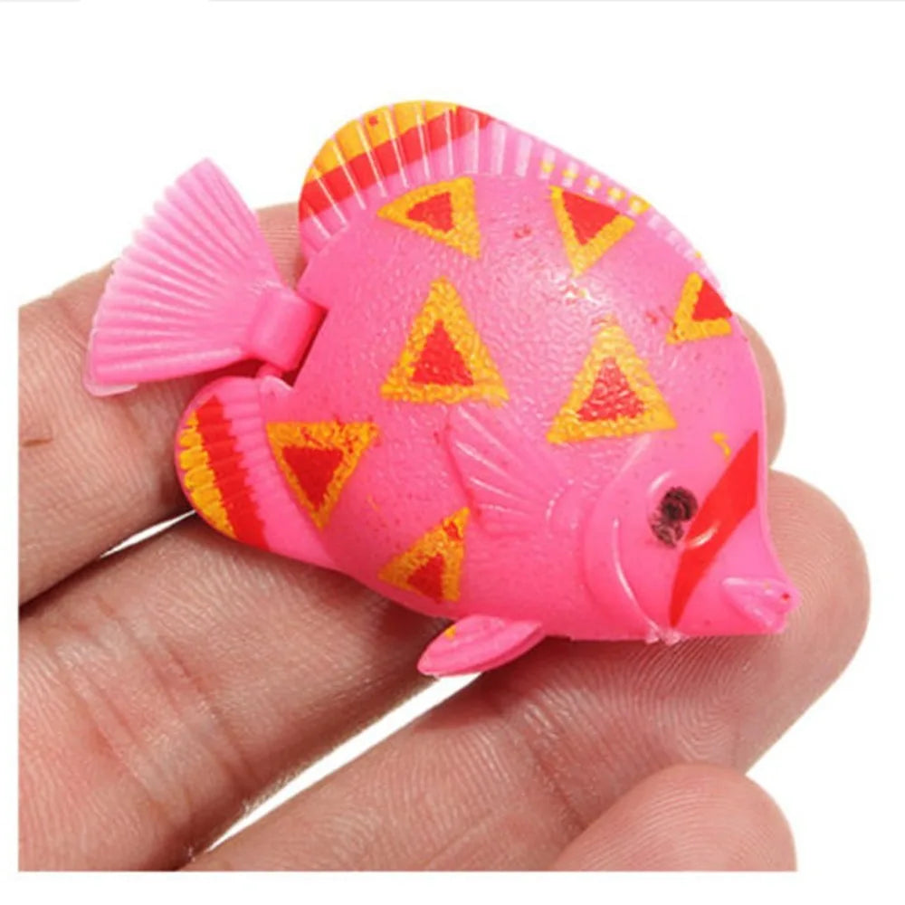 A bright pink artificial tropical fish with yellow triangular markings is held in a hand.