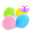 A collection of four silicone hair and scalp massage brushes in green, yellow, pink, and blue.