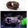 Resin broken barrel fish tank decoration covered in moss placed in a dark aquarium setting