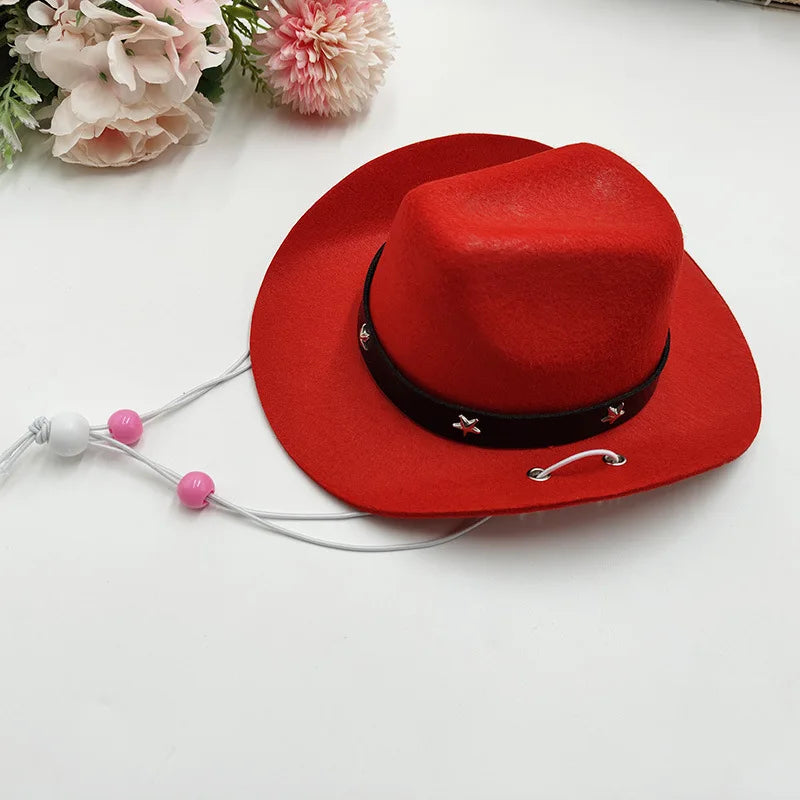 A bright red felt cowboy hat with a black band and white cord, resting on a white surface next to pink flowers.