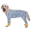 A light-colored dog wearing a long-sleeved jumpsuit with a cartoon animal print featuring small yellow and white figures.