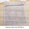 Bolsa de ropa reutilizable de malla blanca con cremallera sobre una superficie de madera.
