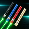 A collection of five high power green laser pointers, including black, blue, red, and gold models, shining beams on a dark su