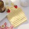 Yellow knitted dog vest with red strawberry accents lying on a white surface.