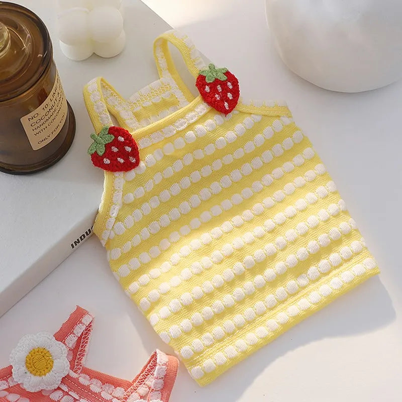 Yellow knitted dog vest with red strawberry accents lying on a white surface.