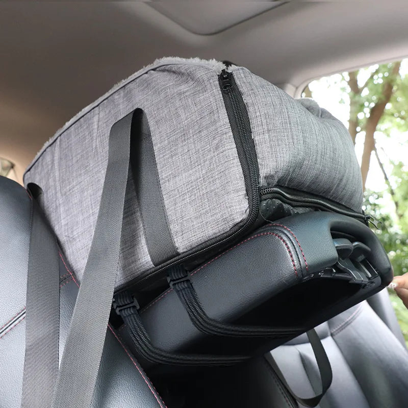 A portable pet car bed with a safety strap is shown placed in the back seat of a vehicle.