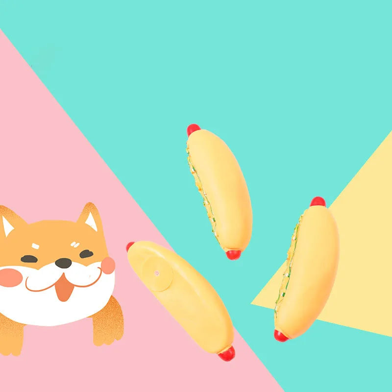 Three yellow hot dog shaped squeaky chew toys are scattered on a pink and teal background.