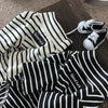 Black and white striped thermal dog sweater with a 'Good luck' logo lying on a wooden surface.