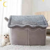 A gray removable dog house pet bed with a soft gray cover sits on a white fluffy rug.