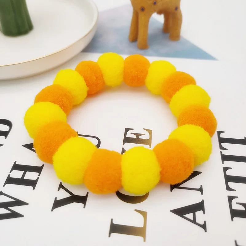 A yellow and orange rainbow flower pet collar and bow tie set displayed on a white surface.