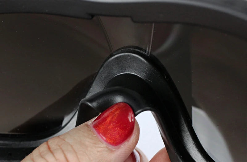 A hand is adjusting a black dog eye protection sunglass on a dark gray lens.