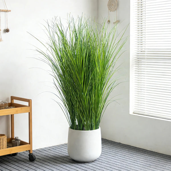 A tall bouquet of green artificial reed grass in a white pot displayed indoors.