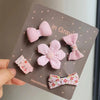 Un paquete de cinco lazos de tela rosa hechos a mano para mascotas, clips de pelo para perros y gatos, mostrados en una tarje