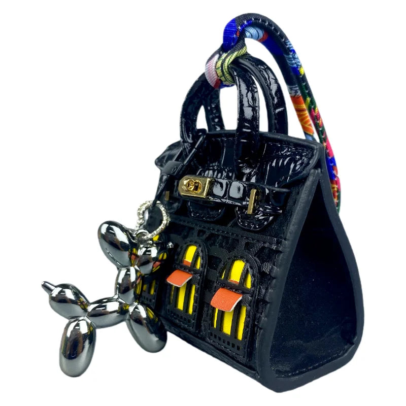 Black mini house-shaped bag with a puppy keychain charm and colorful braided cord