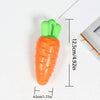 An orange carrot shaped squeaky chew toy for dogs with a green handle, shown next to a ruler.